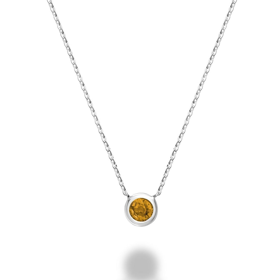 A close-up photo of a citrine necklace in 10kt white gold. The necklace features a bezel-set citrine stone that is a warm golden color. The stone is held securely in place by the gold bezel setting. The chain is also made of 10kt white gold and has an adjustable length.