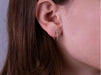 Close-up photo of woman's ears wearing 10kt yellow gold hoop earrings