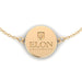 A close-up photo of the Elon University logo, which is engraved on a gold bracelet.
