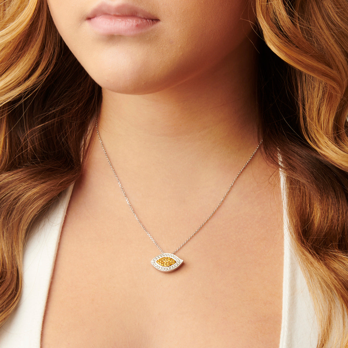A woman elegantly wears the Evil Eye Fancy Yellow Diamond and White Diamond Pendant, its brilliant shine complementing her style.