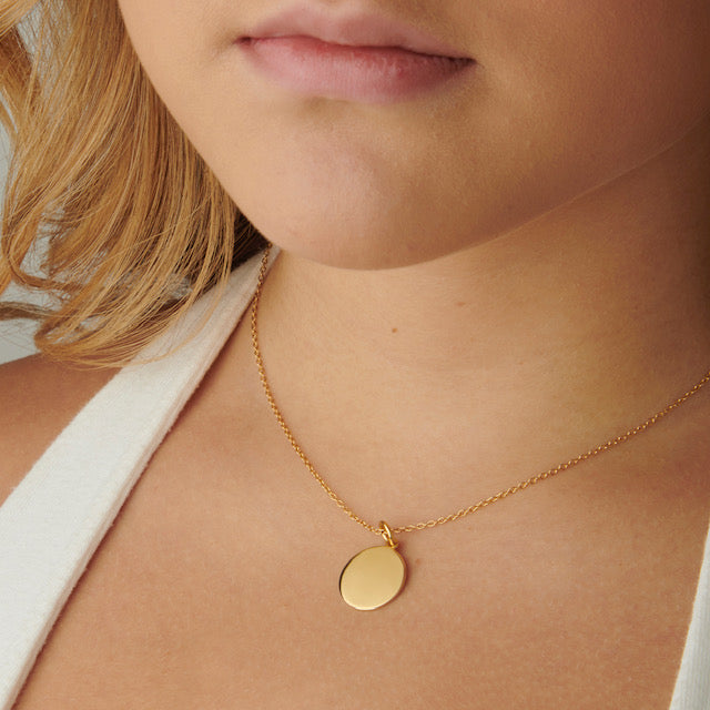 A woman wearing an Emory University Circle Pendant in 14kt yellow gold. The pendant is around the woman's neck.