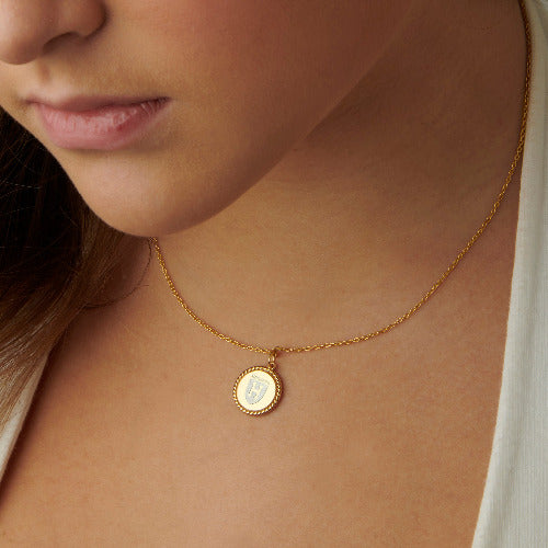  A woman wearing a 14kt yellow gold Harvard Ivy Pendant, showcasing its intricate design and elegant craftsmanship.