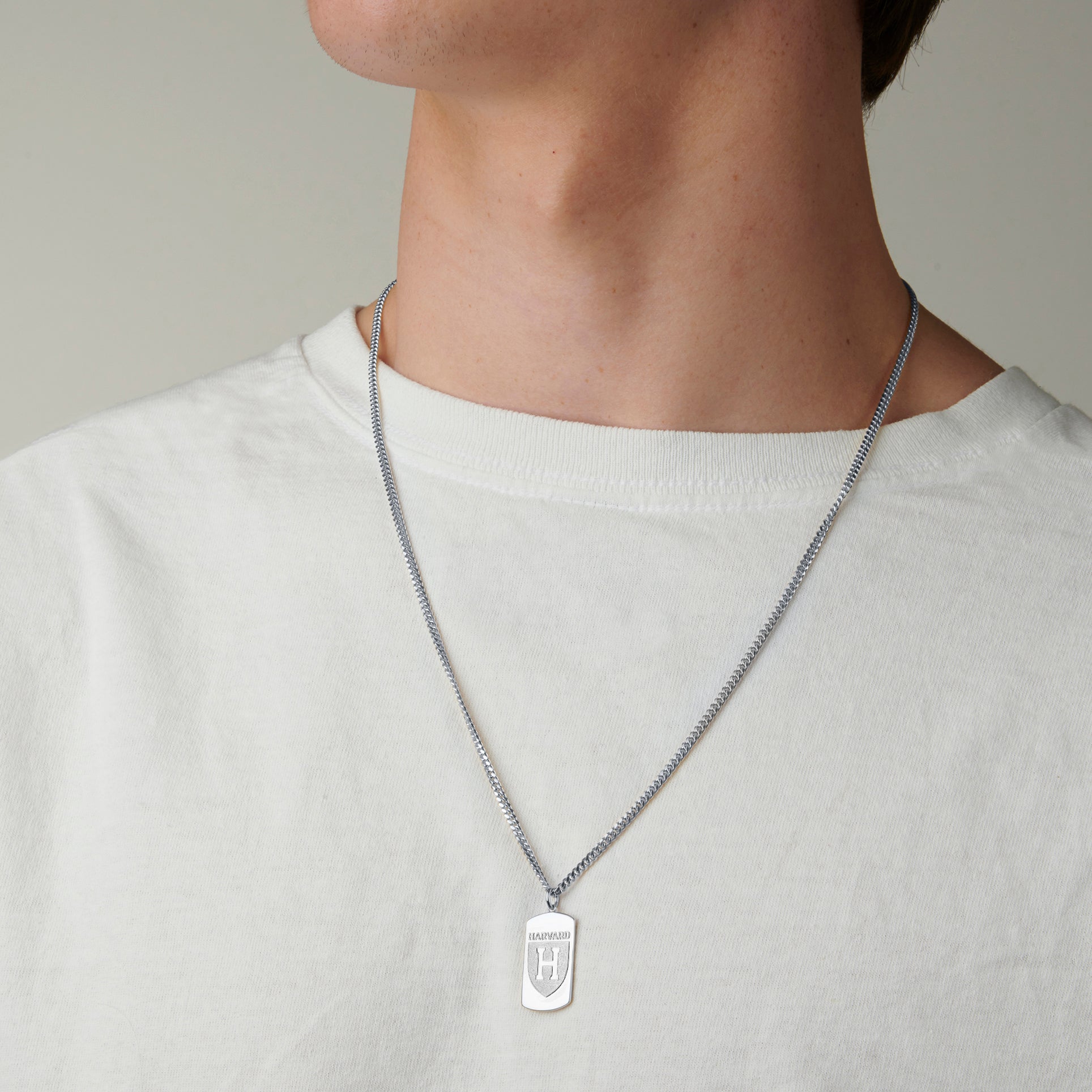 Sterling silver Harvard Squadra Pendant stylishly worn by a man, showcasing the pendant's sleek design and timeless elegance.