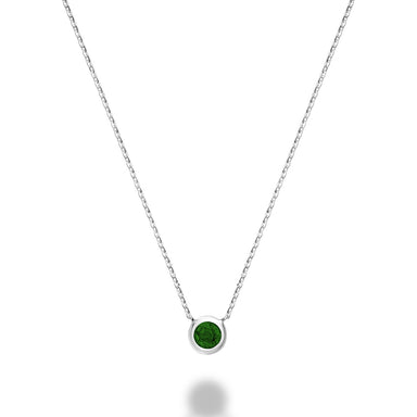 A close-up of a 10kt white gold emerald bezel set necklace. The necklace features a round emerald stone that is set in a gold bezel. The gold is a bright, white color.