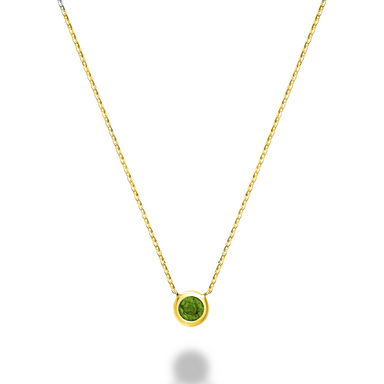 A close-up of a 10kt yellow gold emerald bezel set necklace. The necklace features a round emerald stone that is set in a gold bezel. The gold is a rich, warm yellow color.