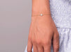 A woman's wrist wearing a diamond pave disc bracelet made from 14kt yellow gold. The bracelet is delicate and feminine, with a sparkling diamond pave design. The woman's wrist is in focus.