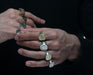 A man's hand, with the focus on various Ivy Rhode class rings, showcasing the different designs and styles available.